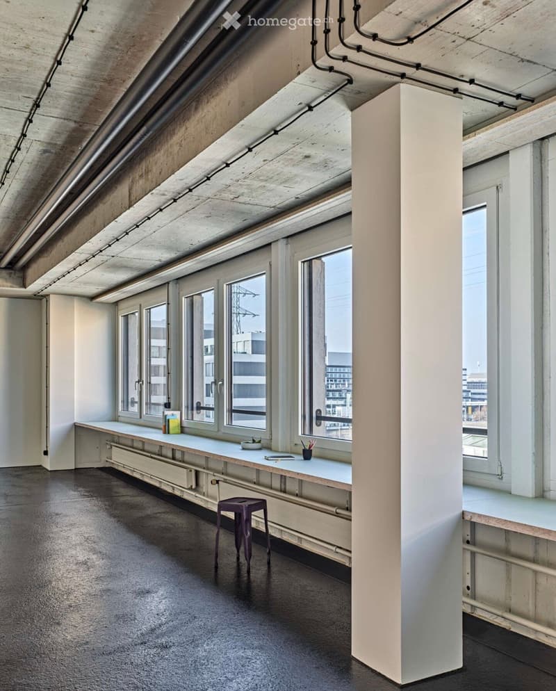 Minimalist room with large windows, exposed concrete ceiling, and a small table with a stool.