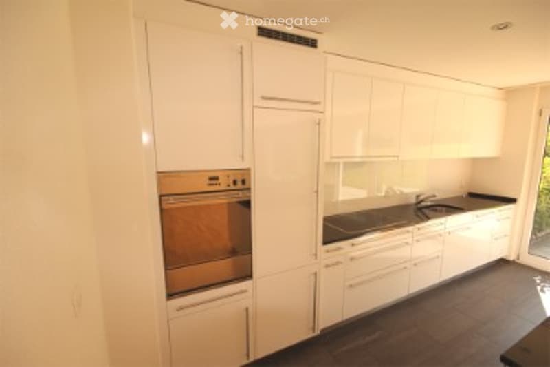 Modern kitchen with white cabinets, stainless steel appliances, and a dark countertop.