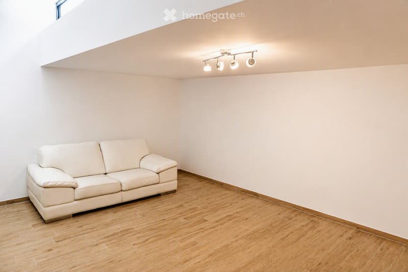 A modern living room with a white leather sofa, wooden flooring, and recessed ceiling lights.