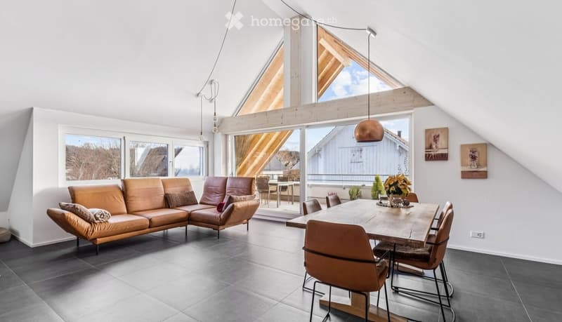 modern attic room with wooden beams, large windows, leather couch, dining table, wooden chairs, flower vase, power outlet