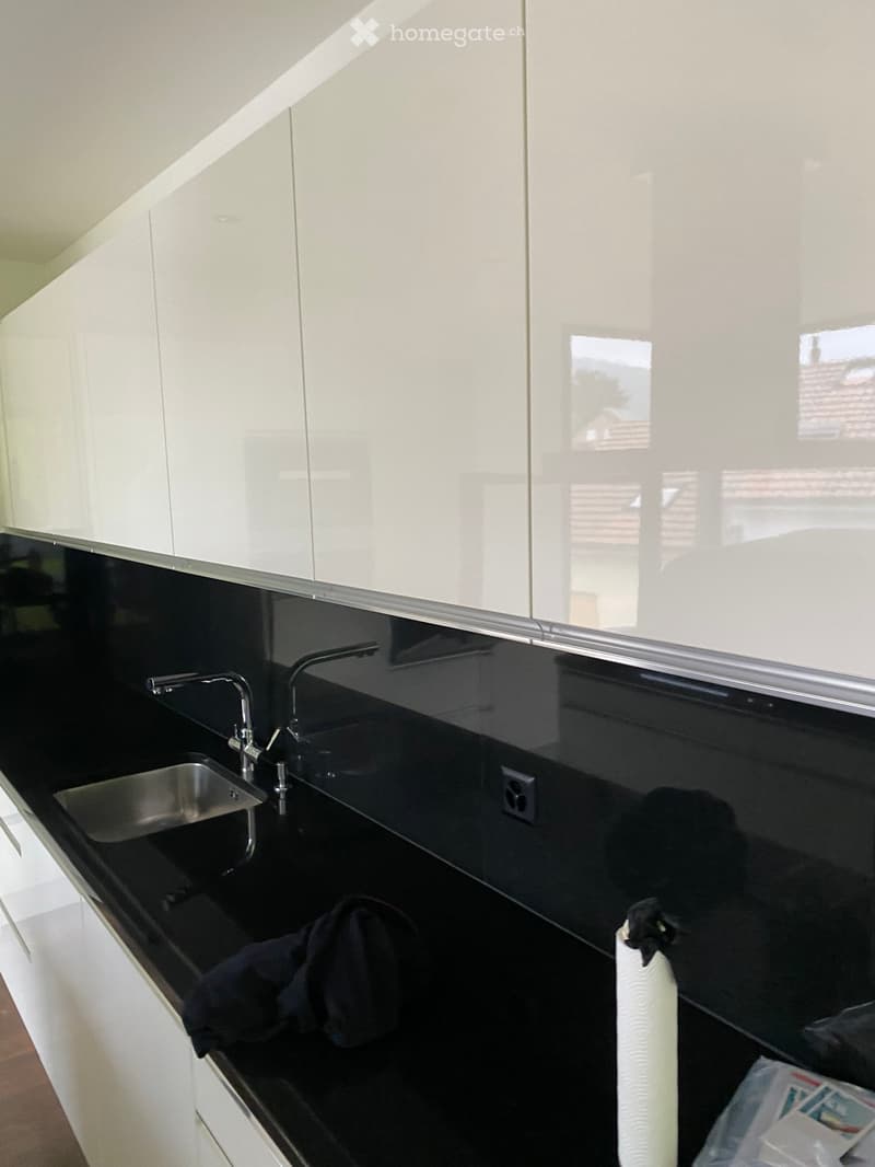 Modern kitchen with white cabinets, black countertops, and a stainless steel sink.