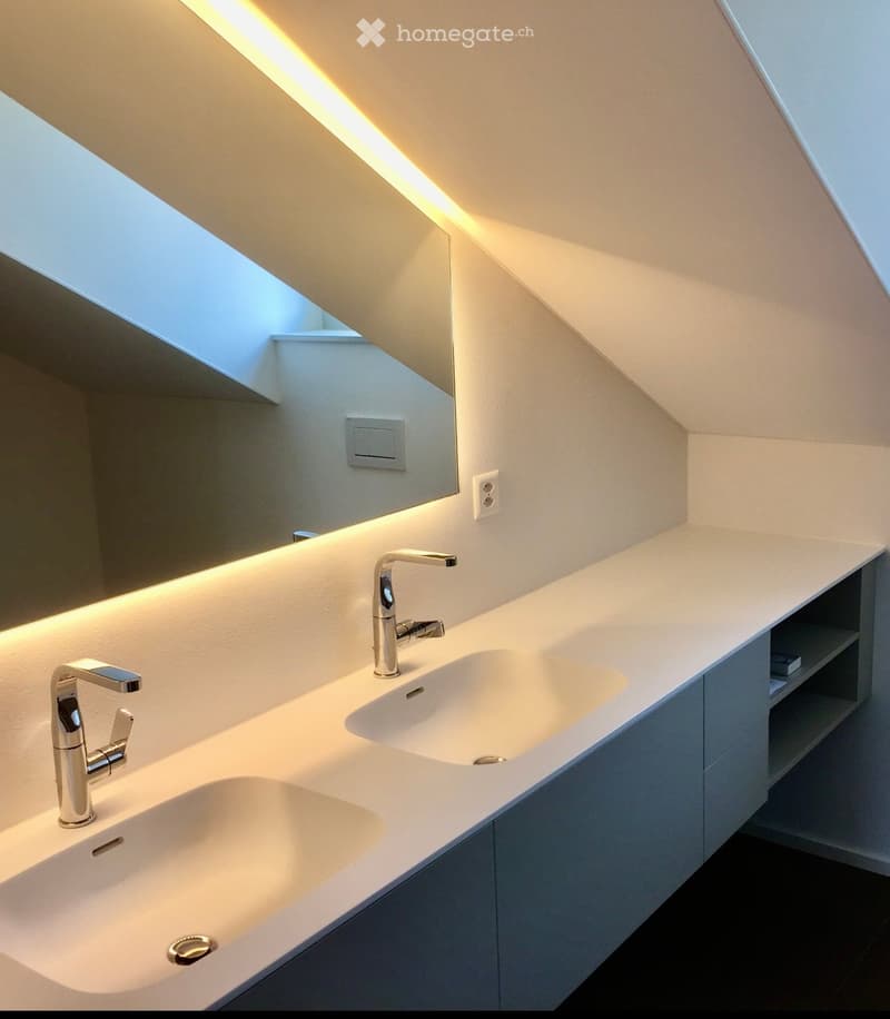 Modern bathroom with a sleek double sink, integrated lighting, and a large mirror. The design features clean lines and a minimalist aesthetic.