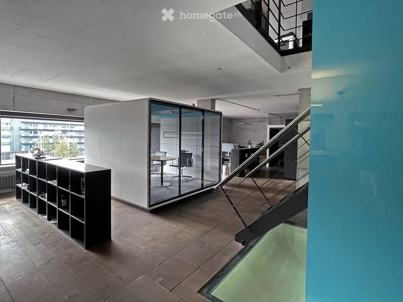 Modern, minimalist room with a glass partition, a staircase leading upwards, a shelf unit, and a small seating area with a table and chairs.