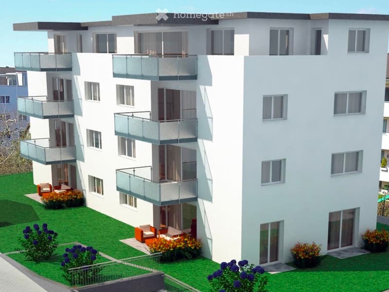Modern multi-story residential building with balconies, large windows, and landscaped surroundings including seating areas and flower beds.