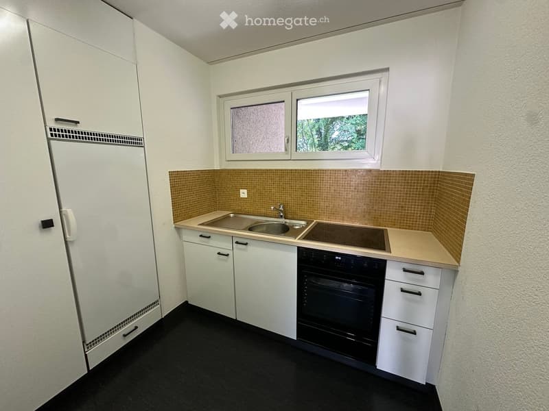 Modern kitchen with white cabinets, a sink, a faucet, and an oven. The backsplash is tiled in a warm brown color, and the countertops are light beige.