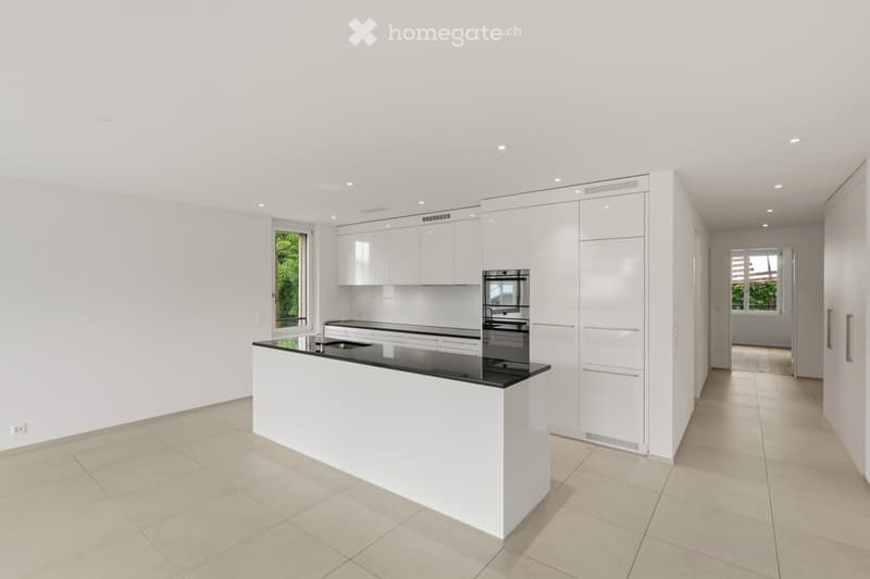 Modern, minimalist kitchen with white cabinets, a black countertop island, and built-in appliances.