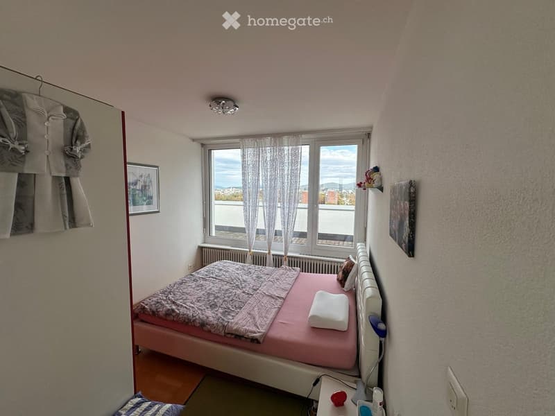 Cozy bedroom with a double bed, nightstand, lamp, and large window with curtains offering a scenic view.