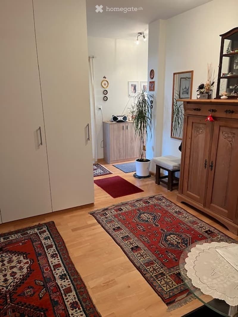 wooden floor, red carpets, wardrobe, sideboard, potted plant, glass table, lamp, framed pictures on wall