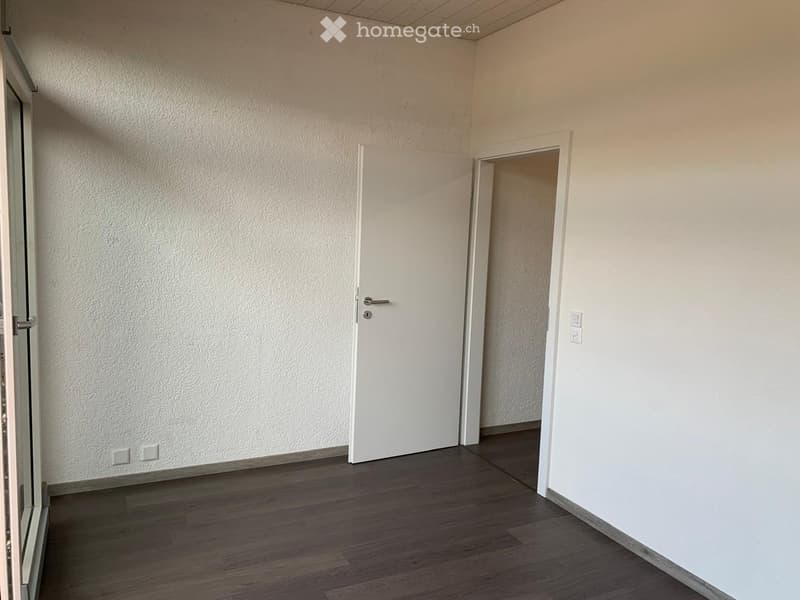 Empty room with wooden flooring, white walls, and a closed white door leading to another space.