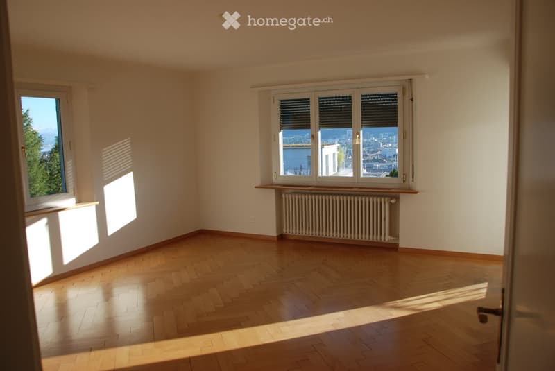 Empty room with wooden flooring, large windows, radiator, and natural light. No furniture or equipment present.