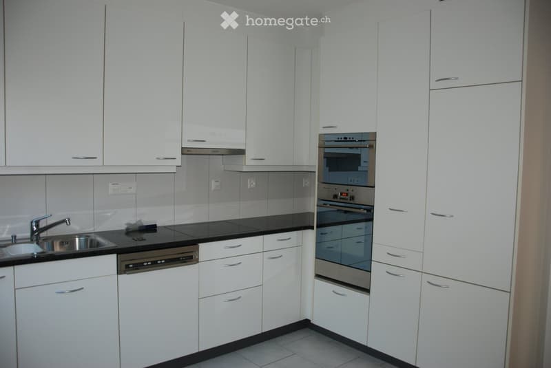 Modern kitchen with white cabinets, stainless steel appliances, and a black countertop.