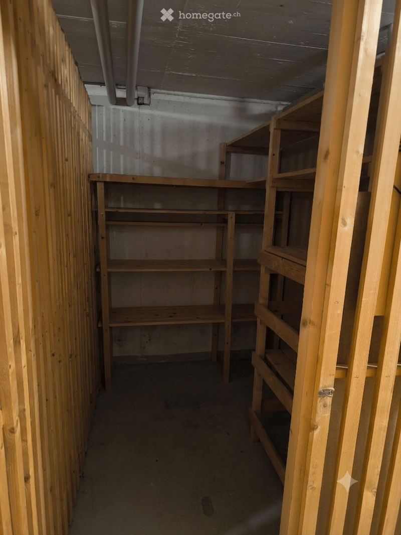 Empty storage room with wooden shelving units and concrete floor, no furniture or equipment.