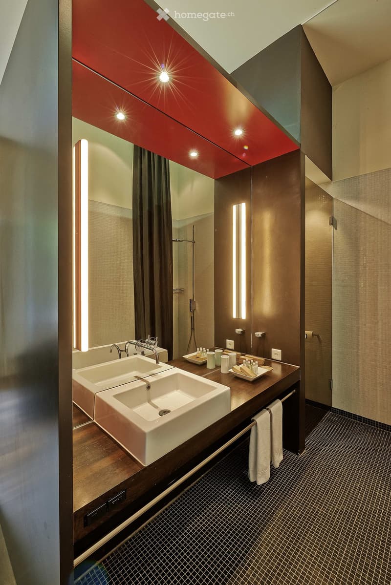 Modern bathroom with double sink, sleek wooden vanity, mirrored cabinet, and built-in lighting.