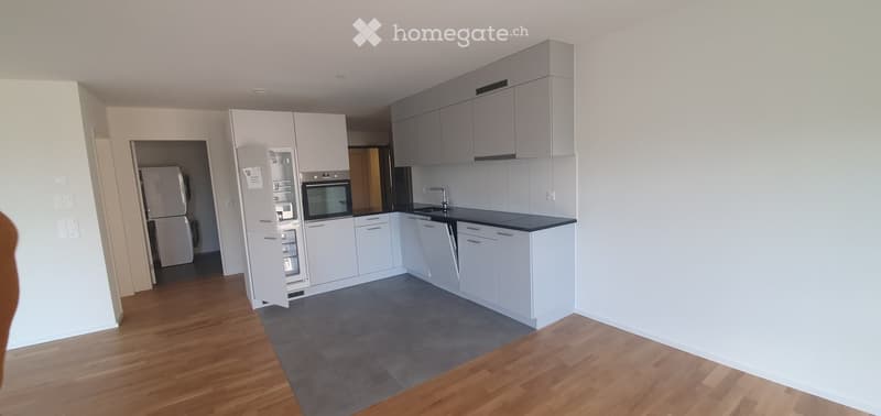 Modern kitchen with white cabinets, stainless steel appliances, and a black countertop. Features a refrigerator, oven, sink, and faucet.