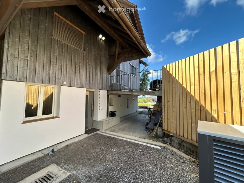 Detached house with wooden exterior, entrance gate, driveway, garage with car, fence, windows