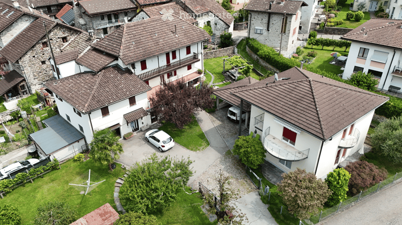 multiple houses, brown roofs, multiple cars in driveways, stone wall, greenery