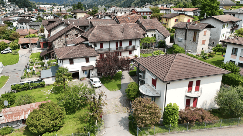 Aerial view of residential area with multiple houses, some with garages, and surrounding greenery.