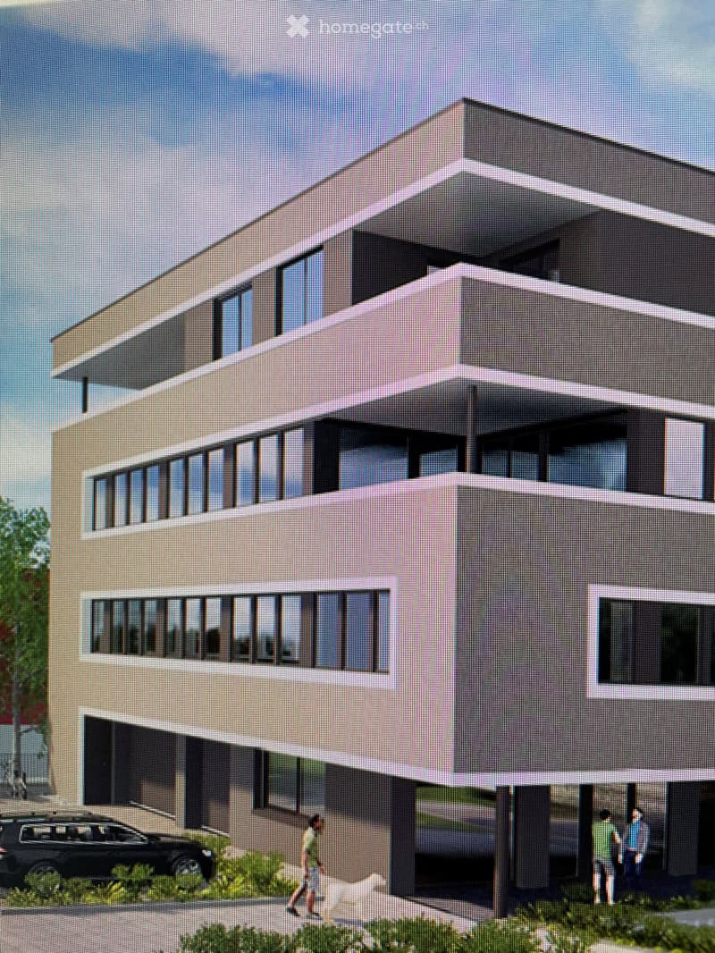 Modern two-story building with large windows and a flat roof, featuring a contemporary design with beige and grey tones.