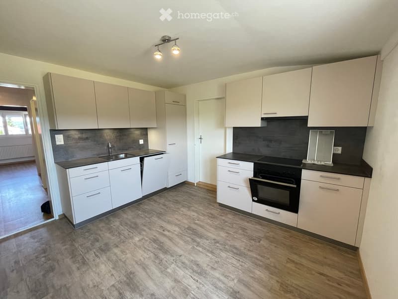 Modern kitchen with white cabinets, black countertops, and a stainless steel sink. Features include an oven, a faucet, and built-in lighting.