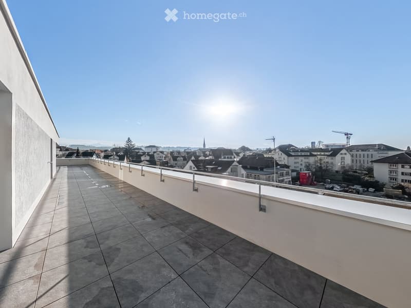 Modern balcony with tiled floor, white railing, and a panoramic view of a cityscape under a clear blue sky.
