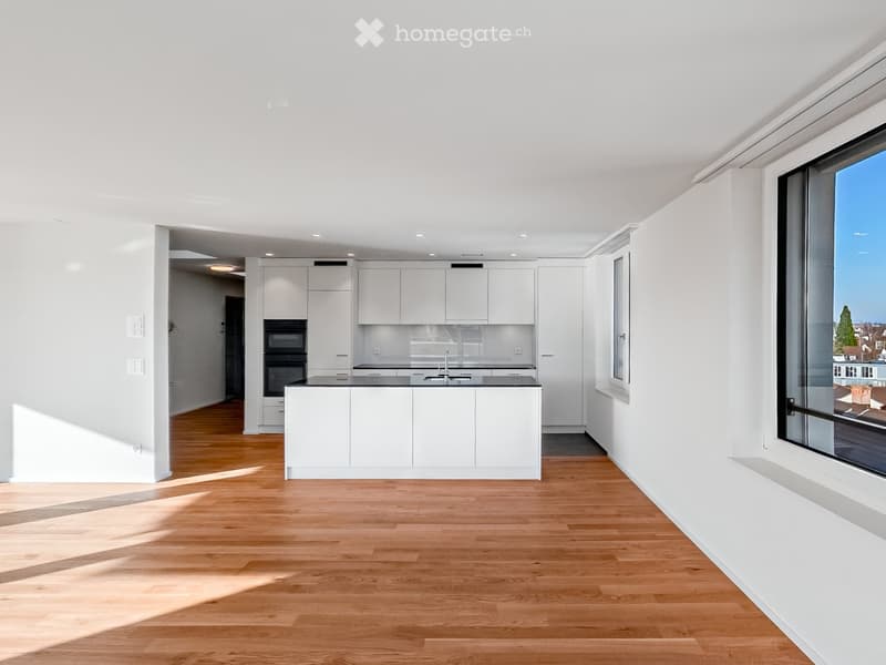 Modern kitchen with white cabinets, a central island, and a large window offering a view of the city.