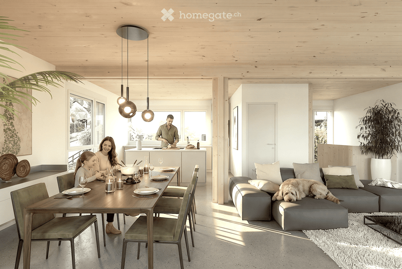 Open-plan living and dining area with a grey sectional sofa, wooden dining table with chairs, pendant lights, and a kitchen island in the background.