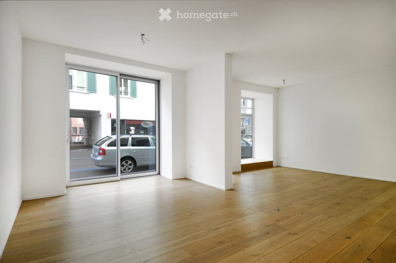 Empty room with wooden flooring, white walls, and large sliding glass door leading to an outdoor area.