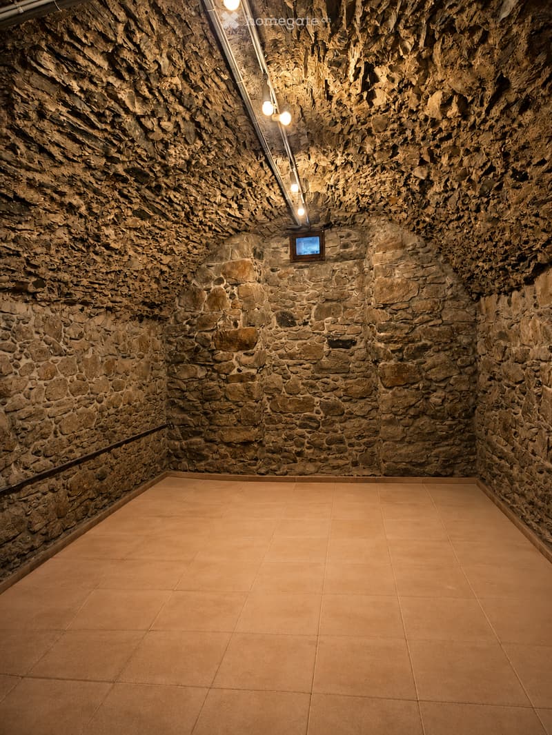 Empty room with stone walls and tiled floor, illuminated by ceiling lights. No furniture or equipment present.