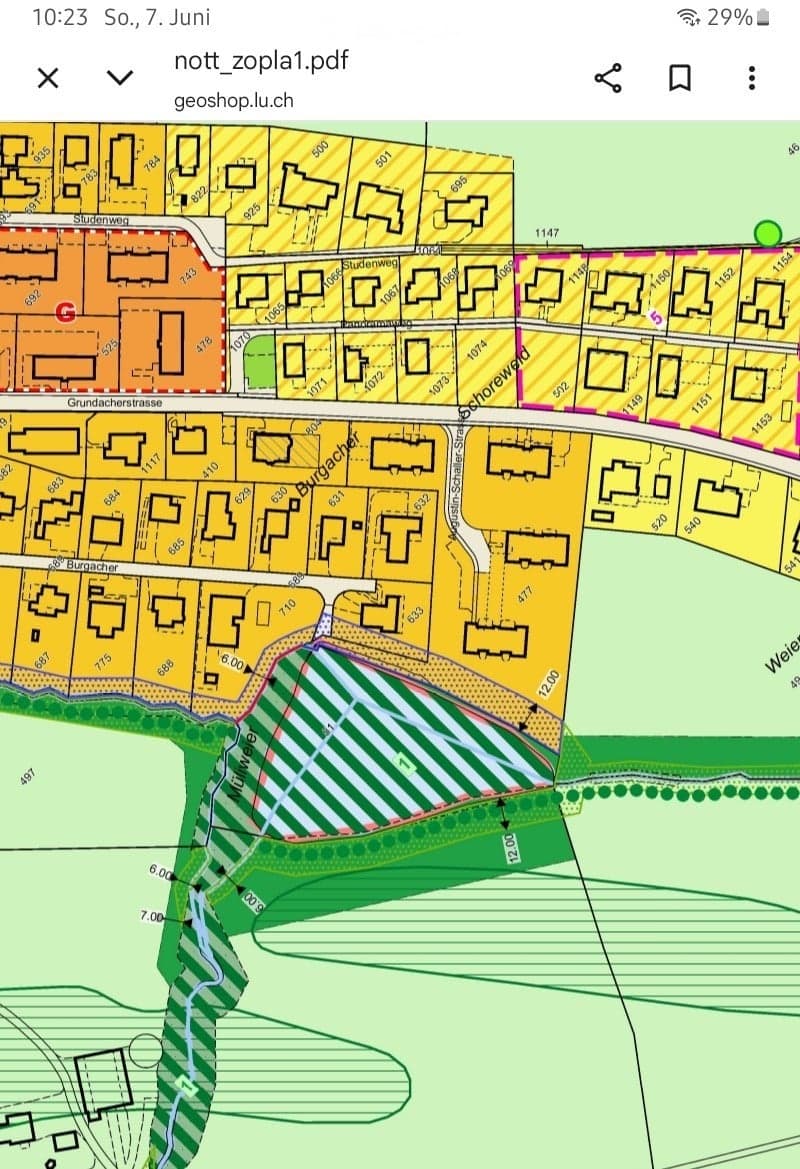 Floor plan showing multiple residential buildings, numbered plots, and surrounding green spaces.