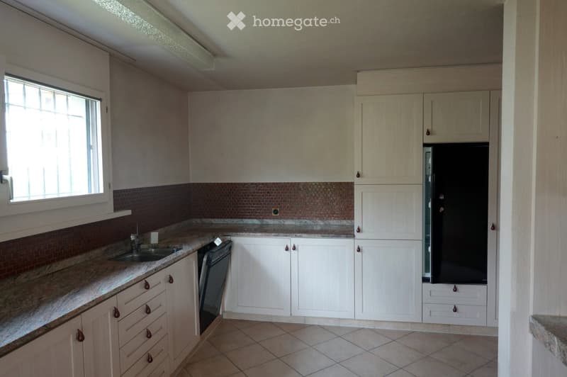 Modern kitchen with white cabinets, granite countertops, and a stainless steel sink. Features a dishwasher and refrigerator, with a window providing natural light.