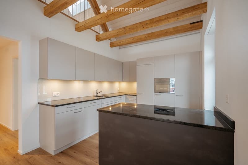 Modern kitchen with white cabinets, dark countertops, and built-in appliances, including an oven and sink.