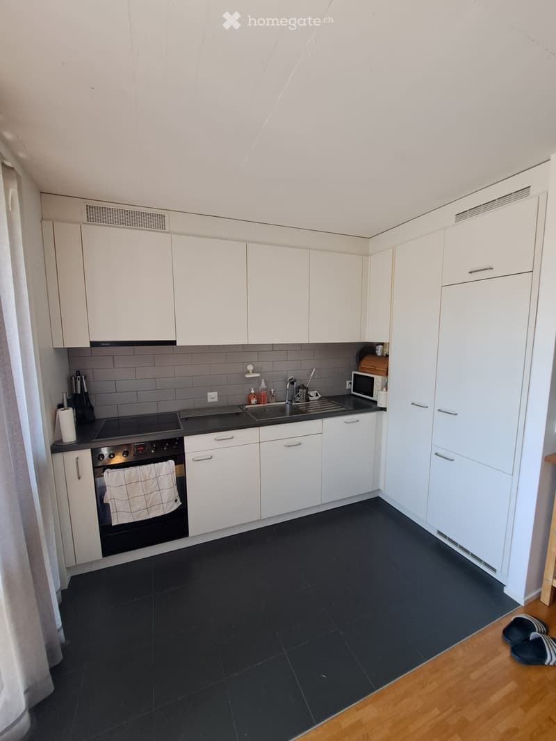 Modern kitchen with white cabinets, black countertops, and stainless steel appliances, including an oven, microwave, and sink.