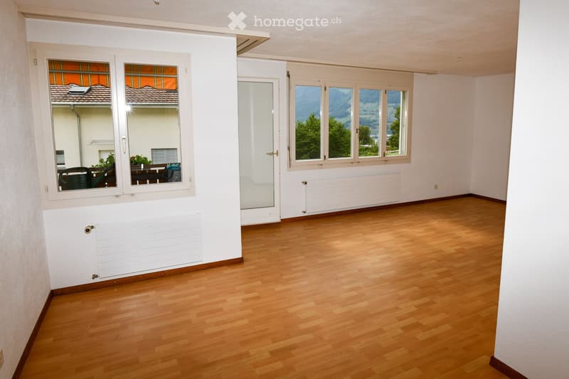 Empty room with wooden flooring, white walls, large windows, and radiators. No furniture or equipment present.