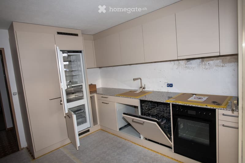 Modern kitchen with light-colored cabinets, granite countertop, stainless steel appliances including a refrigerator, dishwasher, and oven, and a sink with a faucet.