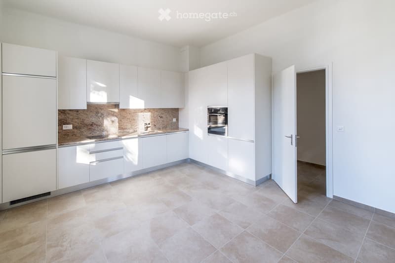 Modern kitchen with white cabinets, stainless steel appliances, and a tiled floor. Features a refrigerator, oven, and sink.