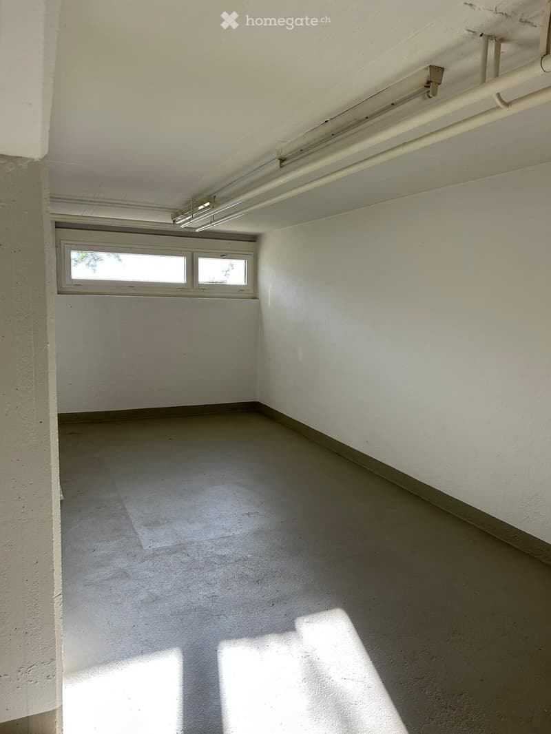 Empty room with white walls, concrete floor, and a single window with two panes allowing natural light to enter.