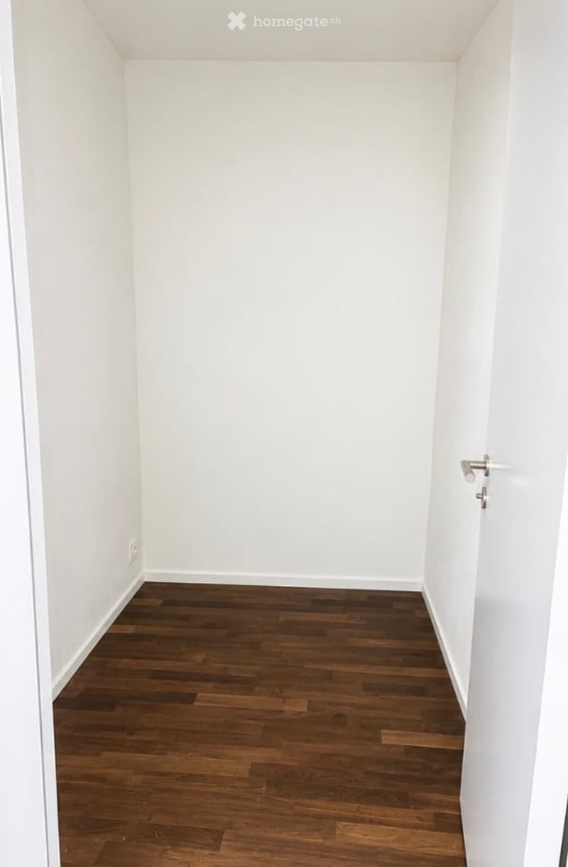 Completely empty room with white walls and dark wooden flooring. No furniture or equipment visible.
