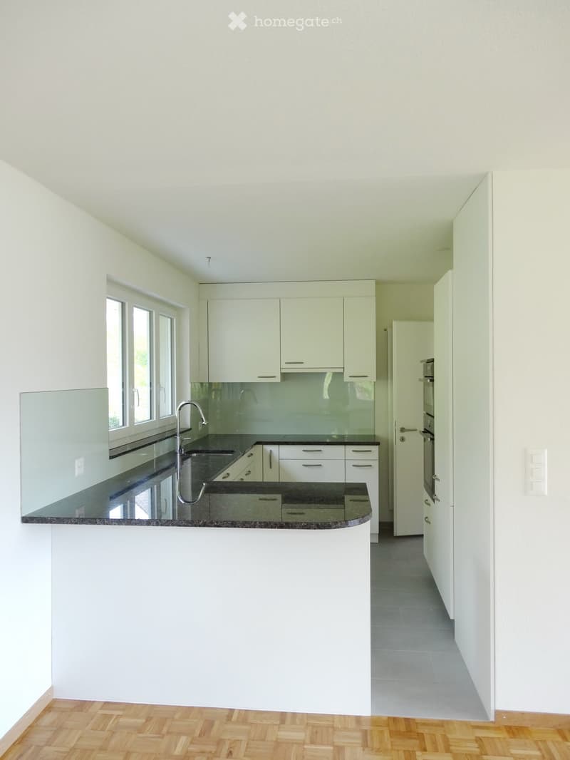 Modern kitchen with white cabinets, black countertops, and a central island. Features a sink with a modern faucet and ample storage space.