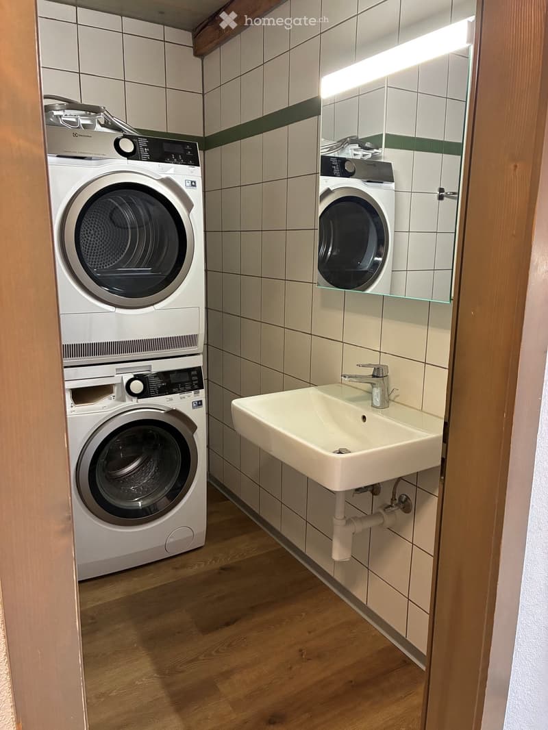 Bathroom with a sink, faucet, and a stacked washing machine and dryer unit.