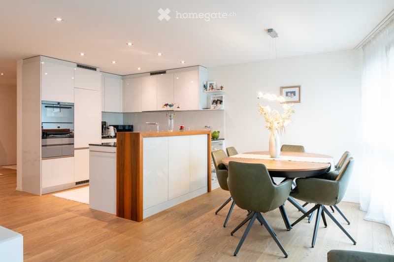 modern kitchen, island countertop, white cabinets, wooden flooring, built-in oven and microwave, dining table and chairs, artwork