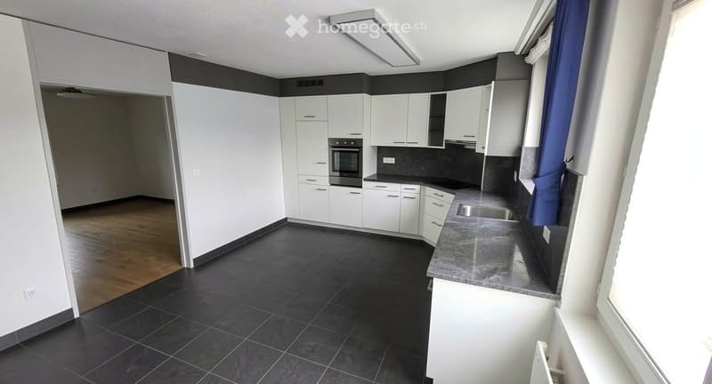 Modern kitchen with white cabinets, black tiled floor, granite countertop, and stainless steel sink.