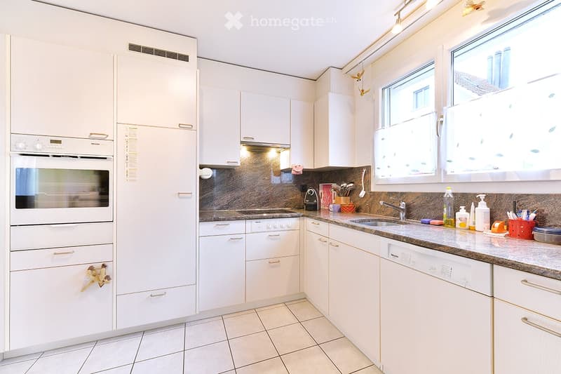 Modern kitchen with white cabinets, stainless steel appliances, granite countertop, and various kitchen items on the counter.