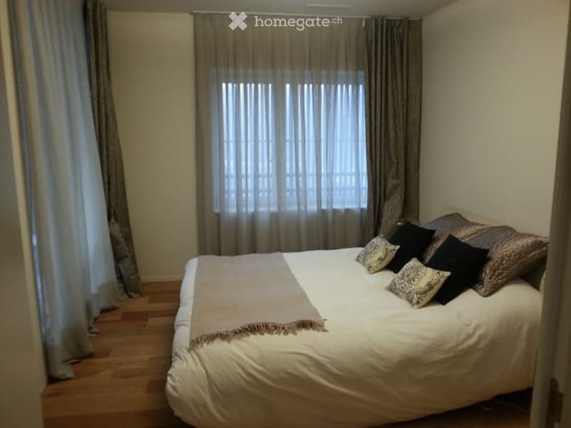 Cozy bedroom with a large bed, multiple pillows, a blanket, and curtains covering the windows.