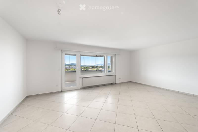 Empty room with white walls, tiled floor, large windows, and a radiator. No furniture or equipment present.