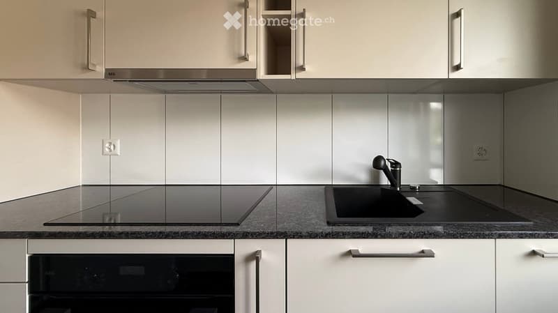 Modern kitchen with white cabinets, stainless steel appliances, and a granite countertop.