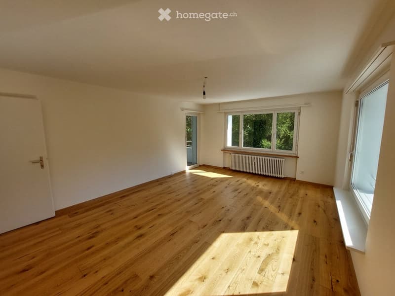 Empty room with wooden flooring, white walls, and large windows allowing natural light to enter. No furniture or equipment is present.