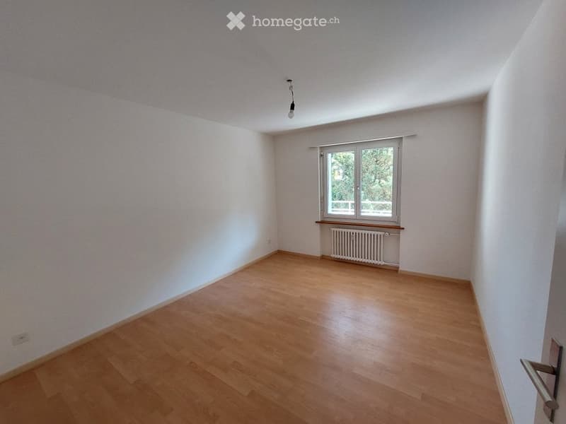 Empty room with wooden flooring, white walls, and a single window with a radiator below it. No furniture or equipment is present.
