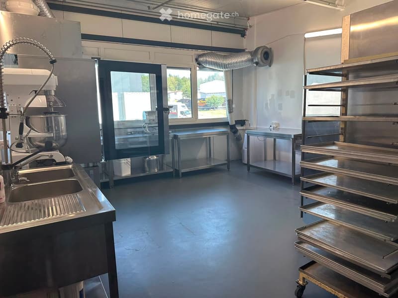 Commercial kitchen with stainless steel sink, faucet, mixing bowl, tables, and shelves.
