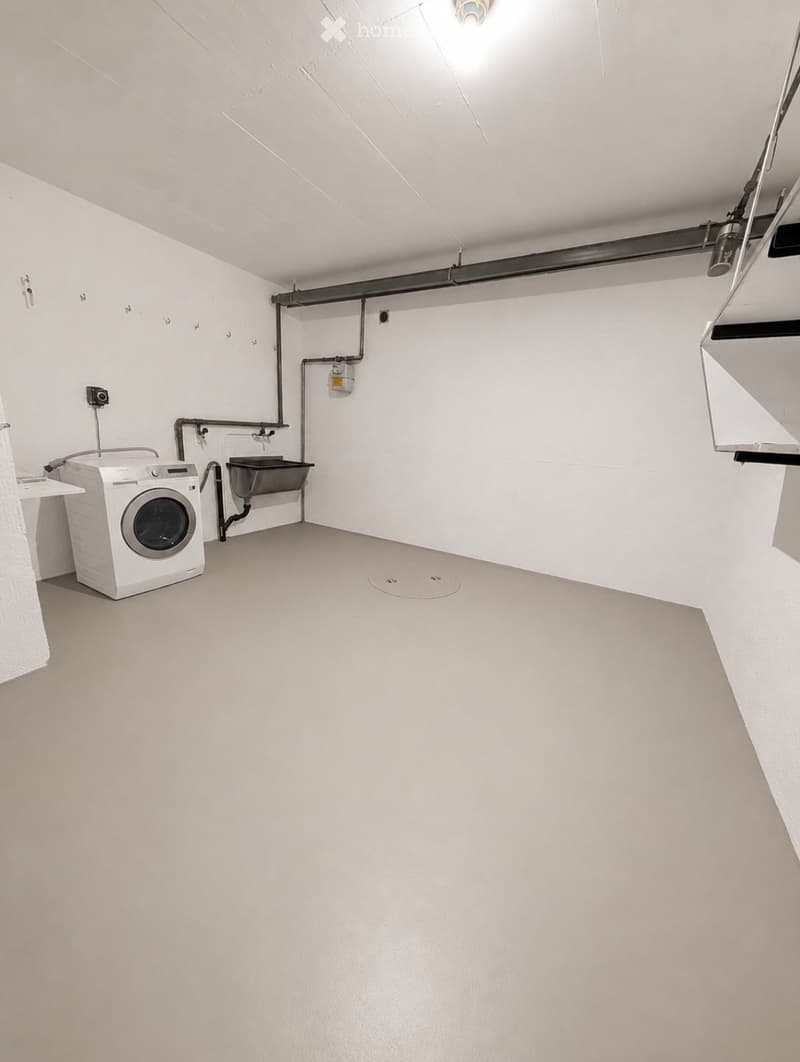 Clean, minimalist bathroom with a white washing machine, grey floor, and white walls.