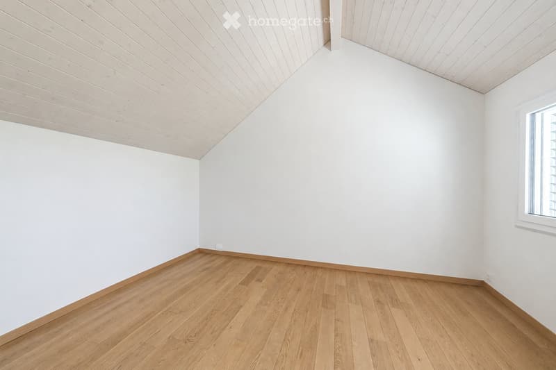 Empty room with white walls, wooden floor, and a window on one side.